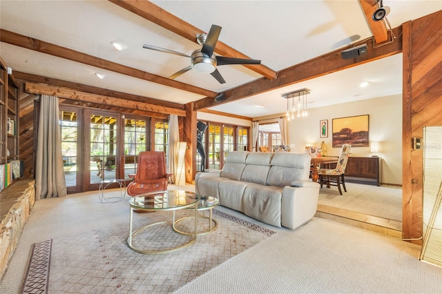 living room featuring beamed ceiling, carpet floors, ceiling fan, and wood walls