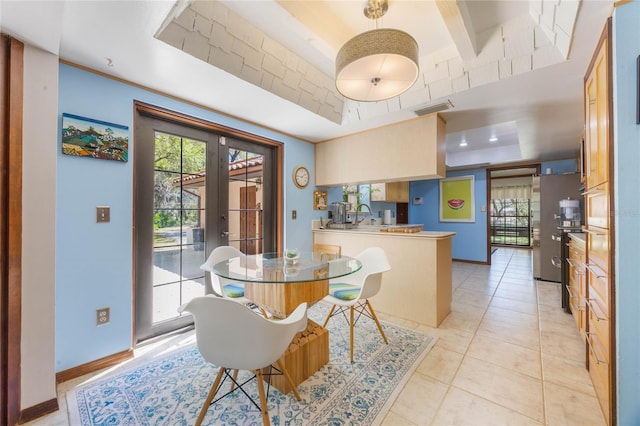 dining room with a raised ceiling, a healthy amount of sunlight, visible vents, and baseboards