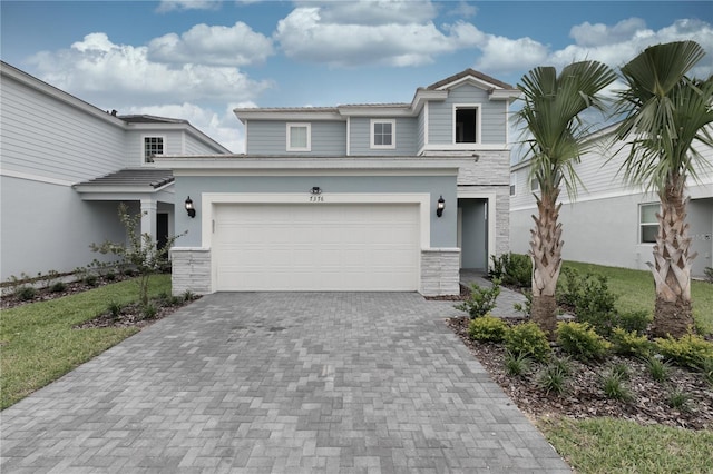 view of front of property featuring stucco siding, a garage, stone siding, a tile roof, and decorative driveway