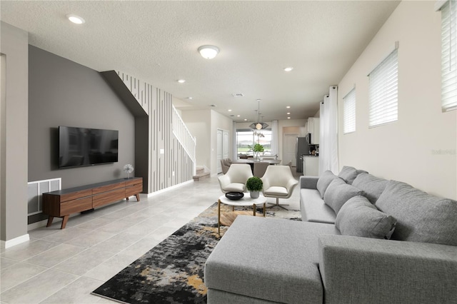 living area featuring stairs, visible vents, a wealth of natural light, and a textured ceiling