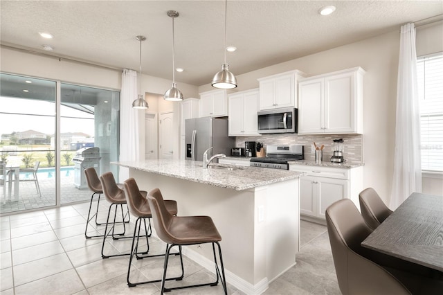 kitchen with a sink, a kitchen breakfast bar, appliances with stainless steel finishes, and a wealth of natural light