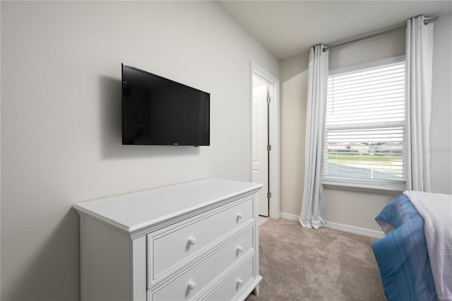 bedroom featuring light colored carpet and baseboards