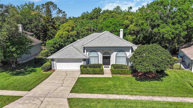 view of front facade with a shingled roof, fence, a garage, driveway, and a front lawn