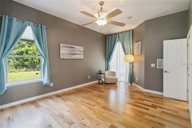 unfurnished room featuring light wood-type flooring, visible vents, baseboards, and a ceiling fan