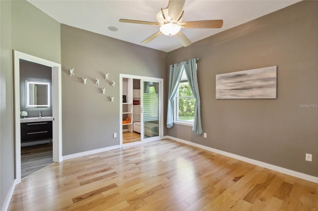 empty room with a ceiling fan, light wood-style flooring, and baseboards