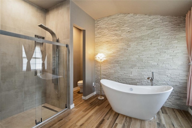 bathroom featuring wood finished floors, a freestanding tub, a shower stall, and toilet