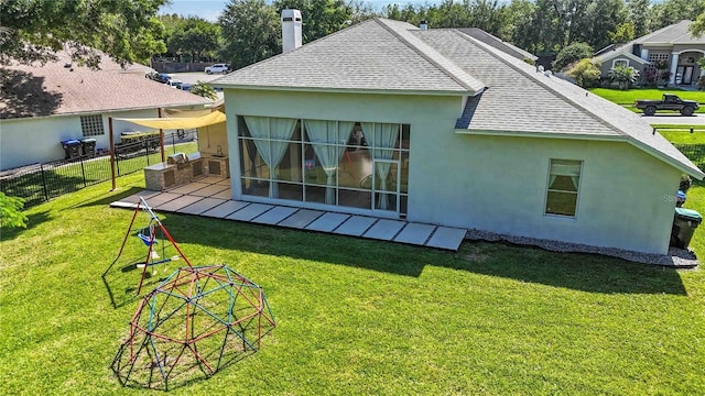 rear view of property featuring a shingled roof, a yard, fence, and stucco siding