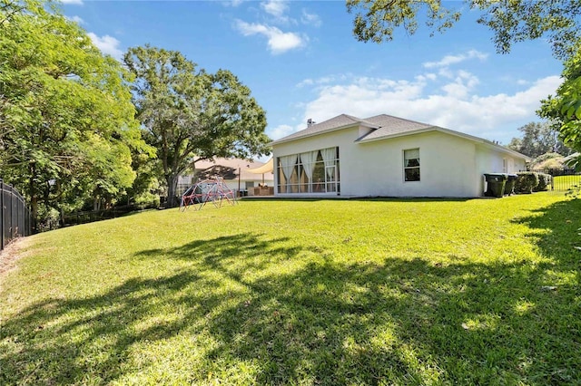 rear view of house featuring a fenced backyard, a lawn, and stucco siding