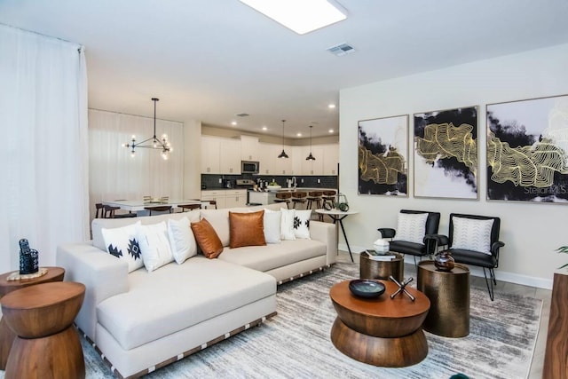 living room with visible vents, baseboards, light wood-style floors, a chandelier, and recessed lighting