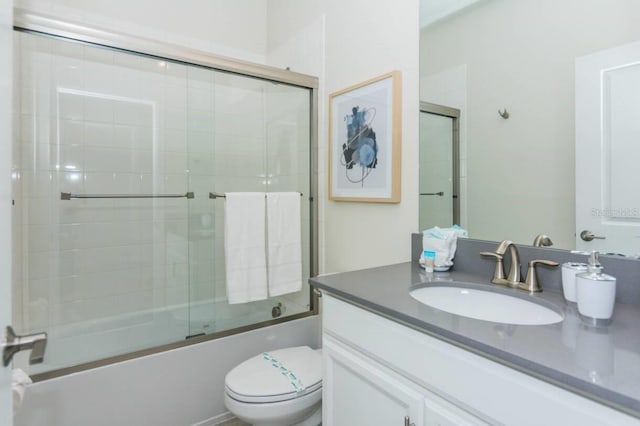 bathroom with shower / bath combination with glass door, vanity, and toilet