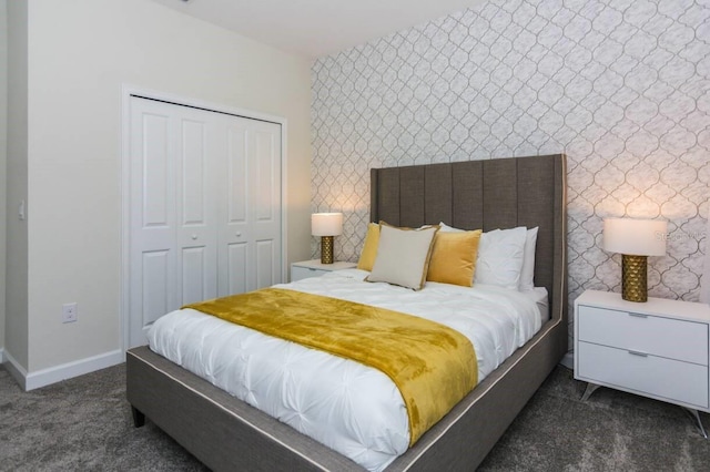 bedroom featuring wallpapered walls, baseboards, dark carpet, and a closet