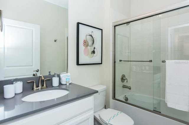 bathroom featuring toilet, enclosed tub / shower combo, and vanity