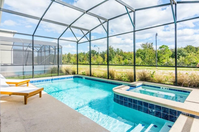 view of swimming pool with glass enclosure, a patio, and a pool with connected hot tub