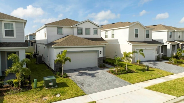 view of front facade with cooling unit, a garage, roof with shingles, decorative driveway, and a residential view