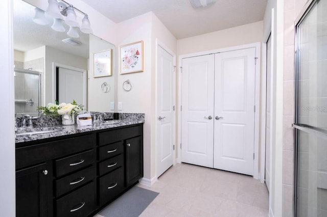 bathroom featuring double vanity, tile patterned flooring, a shower stall, and a sink