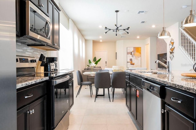 kitchen with decorative light fixtures, stainless steel appliances, visible vents, decorative backsplash, and a sink