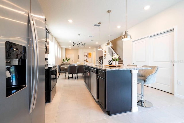 kitchen with appliances with stainless steel finishes, recessed lighting, an island with sink, and a kitchen bar