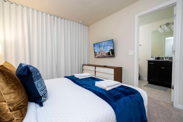 bedroom with light tile patterned floors, connected bathroom, and light colored carpet