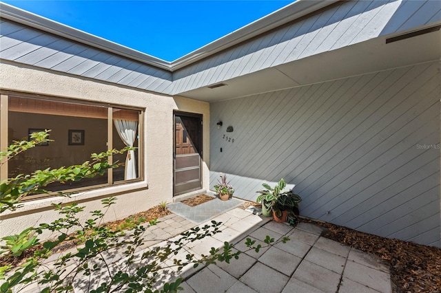 doorway to property featuring a patio area and stucco siding