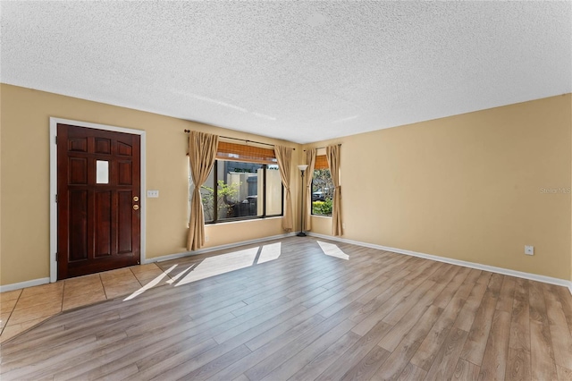 unfurnished living room with wood finished floors, baseboards, and a textured ceiling