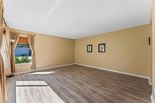 unfurnished room featuring baseboards, a textured ceiling, and wood finished floors