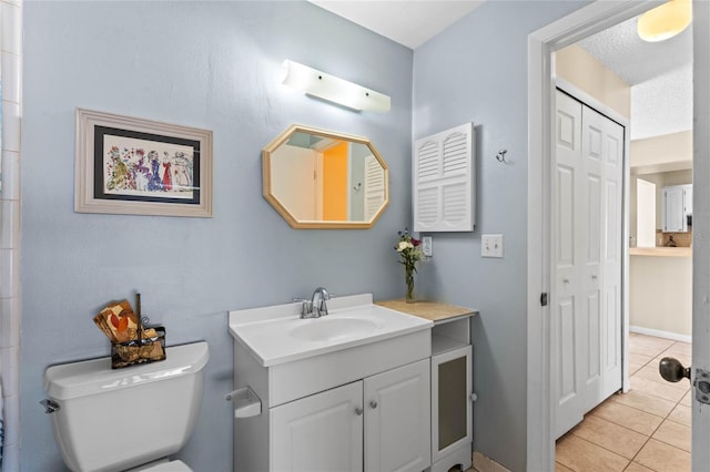 bathroom with tile patterned floors, toilet, a textured ceiling, a closet, and vanity