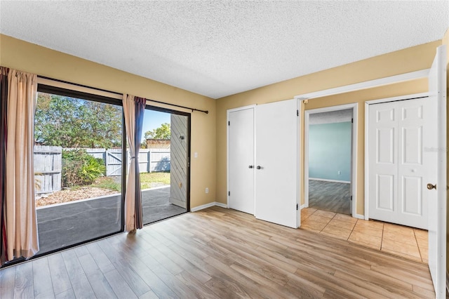 empty room with baseboards, a textured ceiling, and wood finished floors