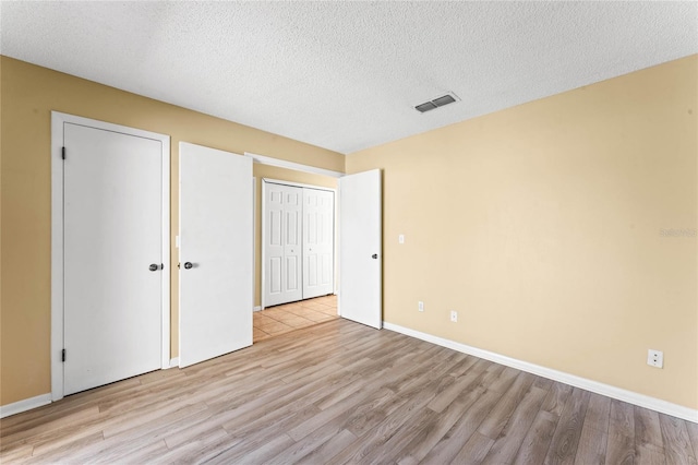 unfurnished bedroom featuring wood finished floors, visible vents, and a textured ceiling