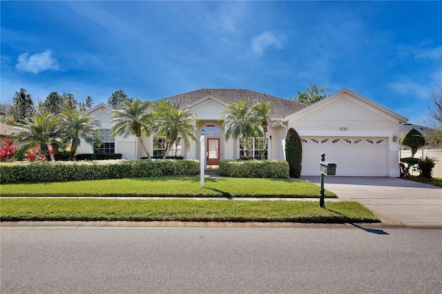 view of front of property with a garage, concrete driveway, a front yard, and stucco siding