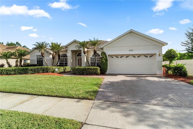 view of front facade with stucco siding, an attached garage, decorative driveway, and a front yard