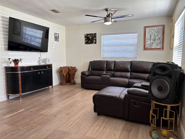 living room with visible vents, a ceiling fan, a textured ceiling, wood finished floors, and baseboards