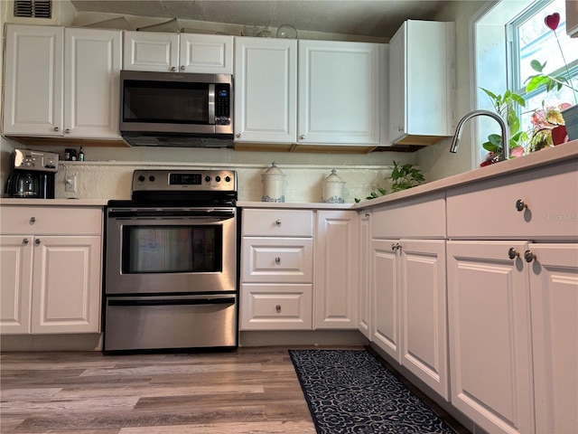 kitchen featuring white cabinetry, light wood finished floors, visible vents, and appliances with stainless steel finishes