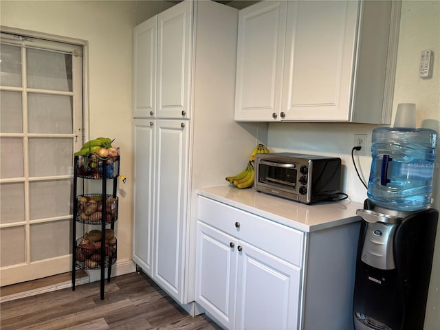 kitchen featuring a toaster, white cabinets, light countertops, and wood finished floors