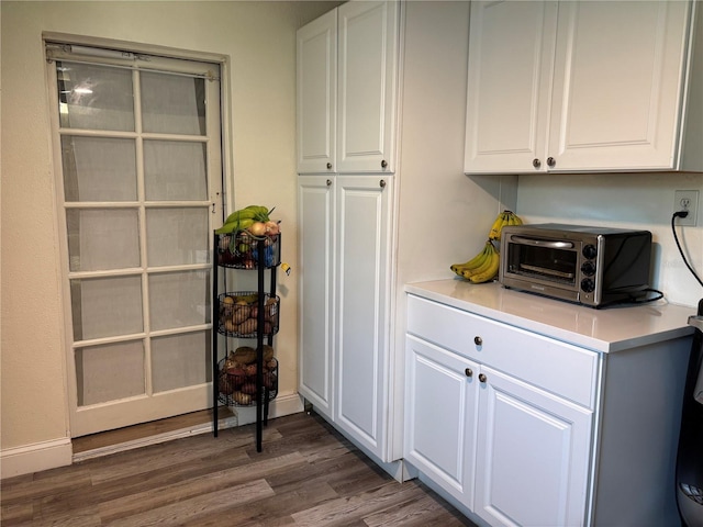 kitchen with a toaster, white cabinets, light countertops, and dark wood-style flooring