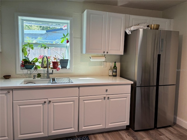 kitchen with dark wood-type flooring, a sink, white cabinetry, freestanding refrigerator, and light countertops