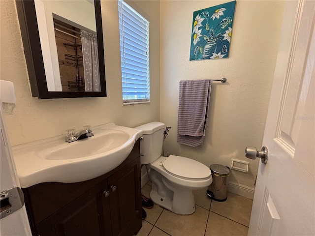 bathroom featuring baseboards, toilet, vanity, and tile patterned flooring