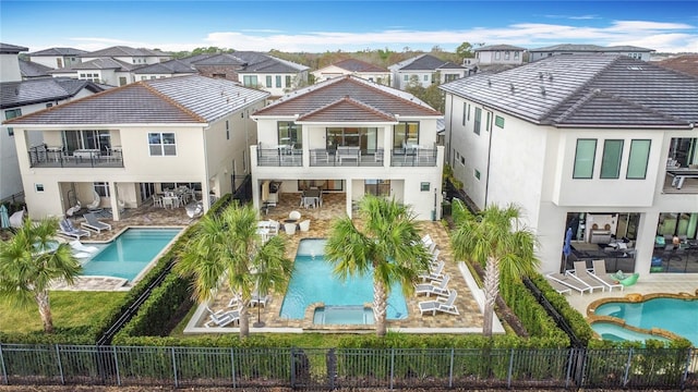 rear view of house featuring a residential view, a fenced backyard, and a pool with connected hot tub