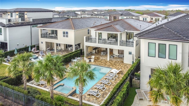 back of property featuring stucco siding, a residential view, a balcony, and a fenced backyard