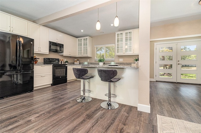 kitchen featuring black appliances, dark wood-type flooring, glass insert cabinets, white cabinetry, and a kitchen bar