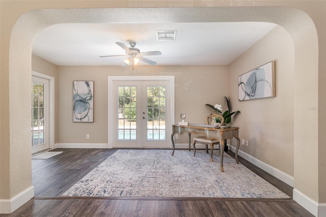 home office featuring french doors, arched walkways, a healthy amount of sunlight, and wood finished floors