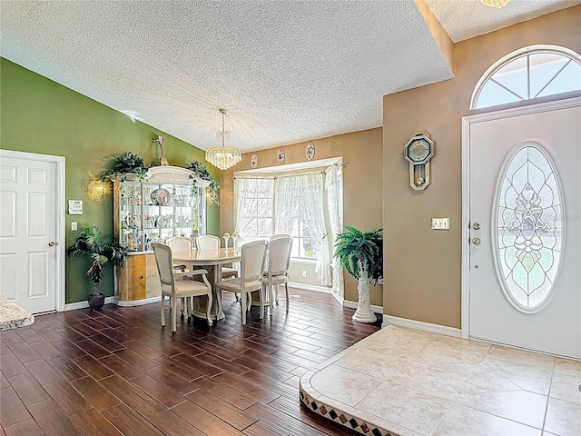 foyer featuring baseboards, lofted ceiling, an inviting chandelier, wood finished floors, and a textured ceiling