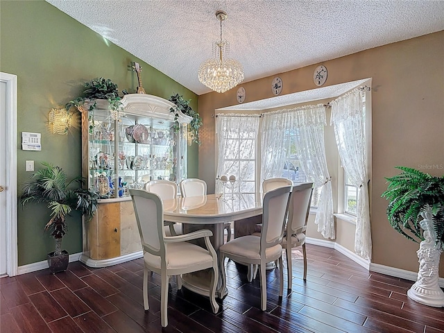 dining room with a notable chandelier, a textured ceiling, lofted ceiling, and wood tiled floor