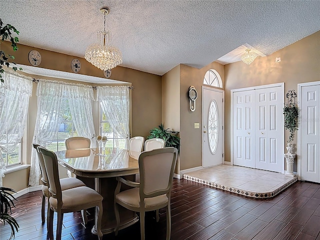 dining space featuring a healthy amount of sunlight, dark wood-type flooring, an inviting chandelier, and vaulted ceiling