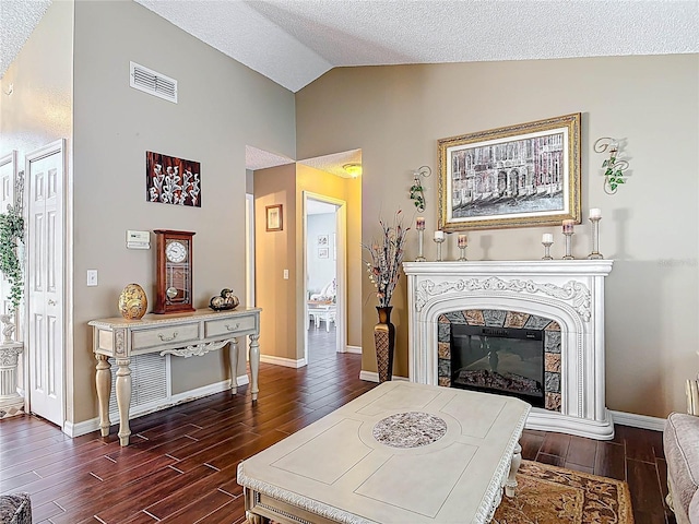 living room with dark wood-style floors, baseboards, visible vents, a tile fireplace, and vaulted ceiling