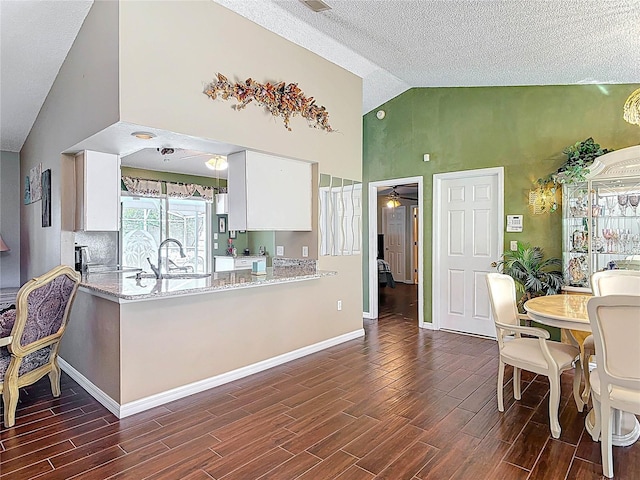 kitchen with baseboards, wood finish floors, white cabinetry, a ceiling fan, and a sink