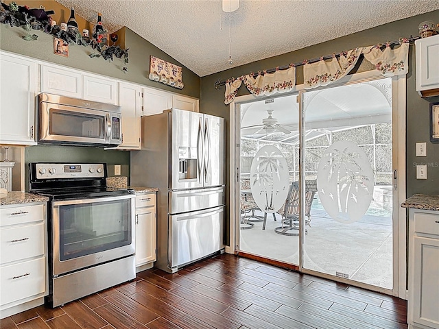 kitchen featuring a ceiling fan, dark wood finished floors, lofted ceiling, appliances with stainless steel finishes, and white cabinetry