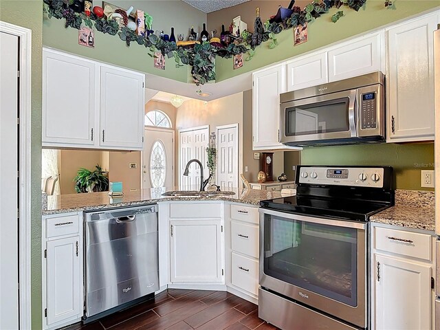 kitchen with a sink, stainless steel appliances, light stone countertops, and white cabinetry