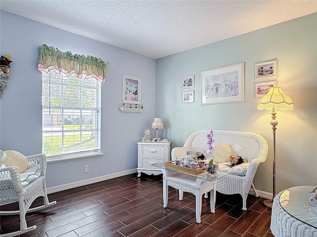 living area with a textured ceiling, baseboards, and wood finish floors