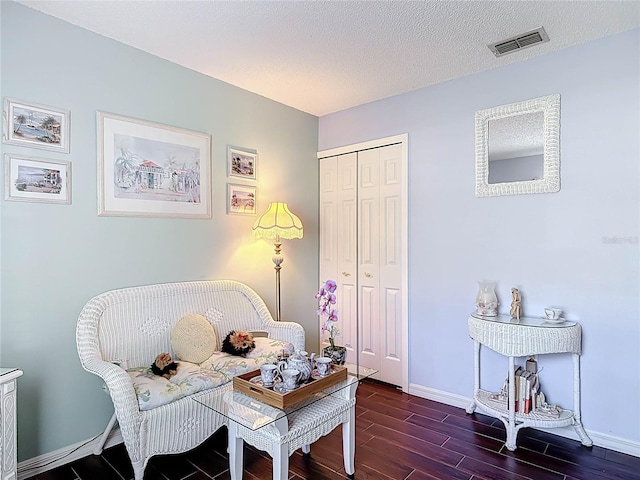 sitting room featuring baseboards, wood finished floors, visible vents, and a textured ceiling