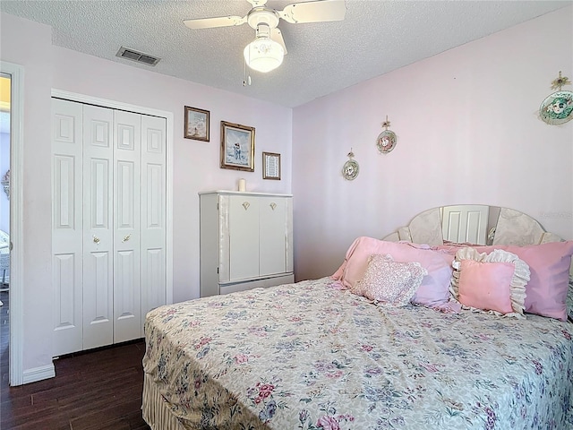 bedroom with visible vents, a ceiling fan, a textured ceiling, dark wood finished floors, and a closet